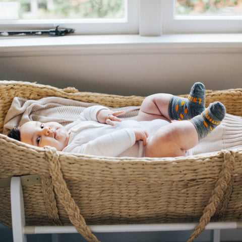 Baby lying in Moses basket wearing Lamington Baby & Toddler's Bay Crew Socks.