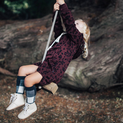 Child wearing Lamington Children's Ash Knee High Socks while playing on rope swing.