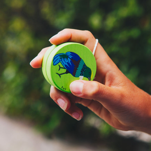 Lifestyle image of Moana Road Green Wooden Tui Yoyo, held in model's hand ready to throw.