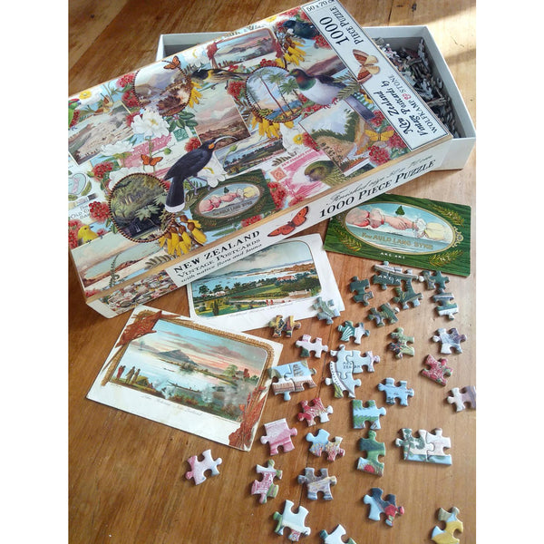 Lifestyle image showing Wolfkamp & Stone Birds & Postcard Jigsaw Puzzle box and pieces spread on table with some of the source postcards used.